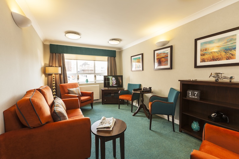 Lounge area with orange couches, blue chairs, and a TV